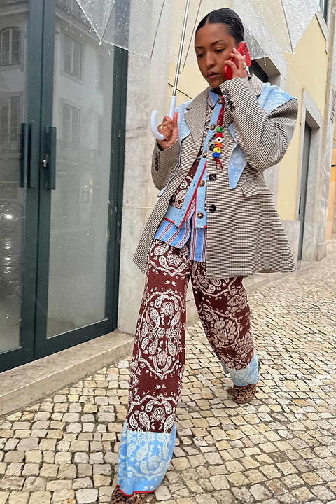 Chocolate Bandana Wide Leg knit trousers with a blue hem, paired with a check blazer on a cobblestone street.