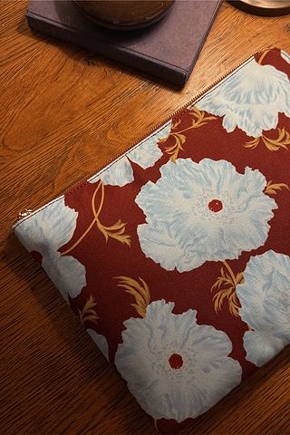 Blue and Burgundy Poppy Laptop Case featuring an in-house designed floral print and gold zip on a wooden table.