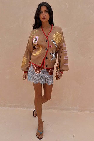 Camel Mystical Cardigan with celestial embroidery and red trim worn over a patterned blue lace dress.