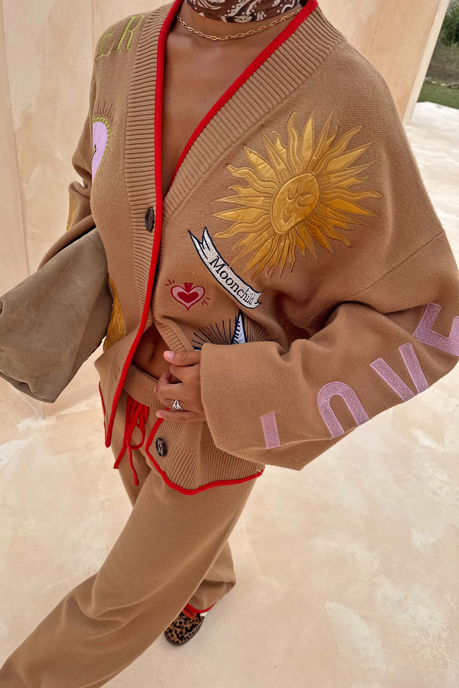 Camel Mystical Cardigan with sun and moon embroidery, red contrast trim and matching knitted trousers.