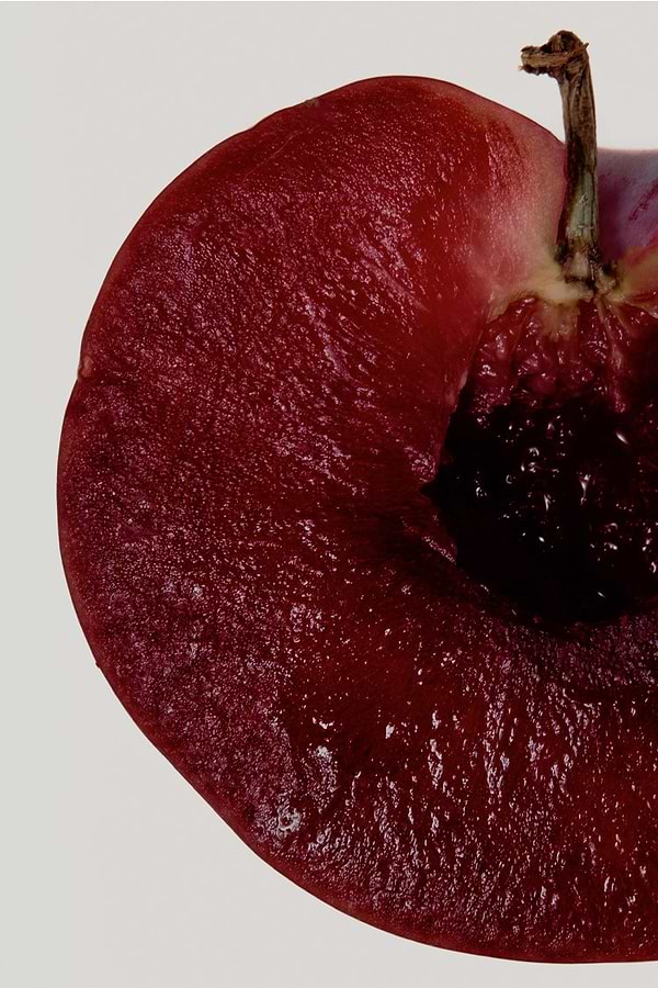 Deep red sliced plum with a dark stone, highlighting a key fragrance note for the NFD Candle 001.