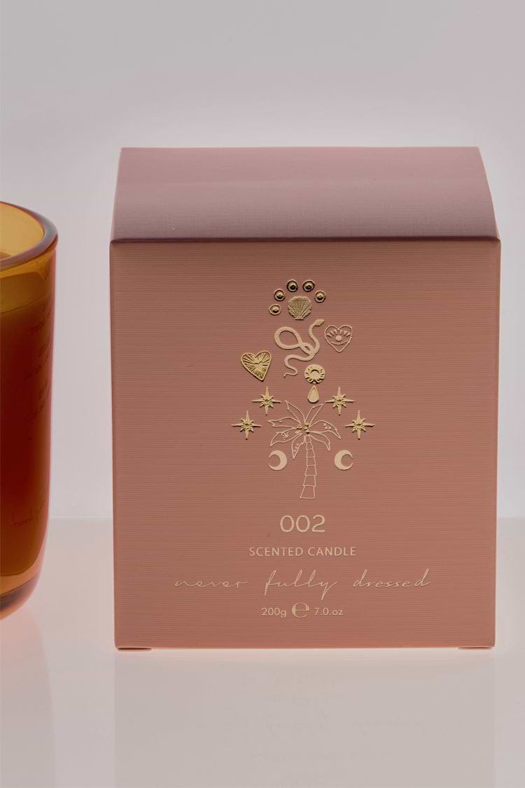 NFD Eau De Parfum Candle 002 packaging in muted pink featuring gold foil palm tree and celestial illustrations.
