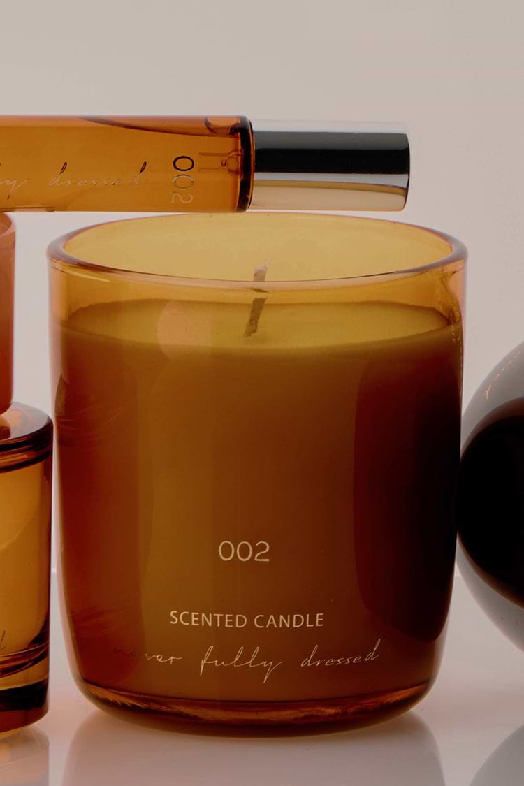 NFD Scent 002 Candle in an amber glass jar with gold lettering, paired with the matching perfume bottle.