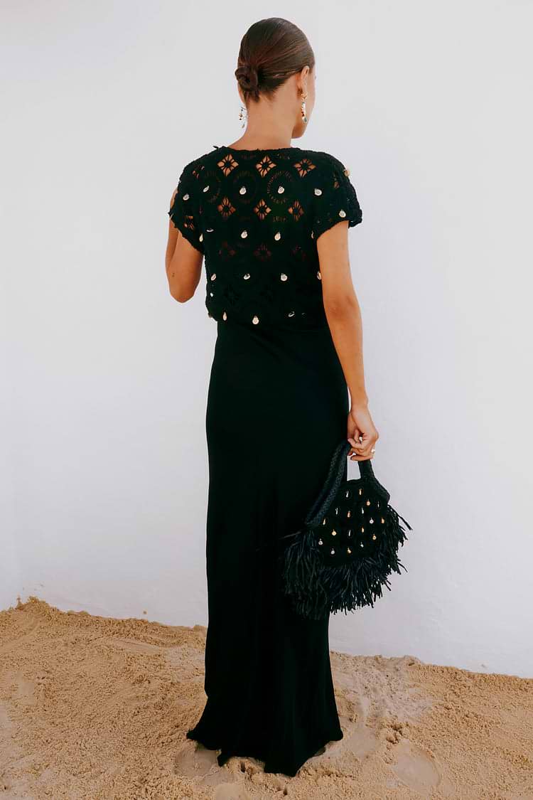 Black Crochet Shell Elodie Dress with gold shell embellishments and a satin skirt, styled with a fringed bag.