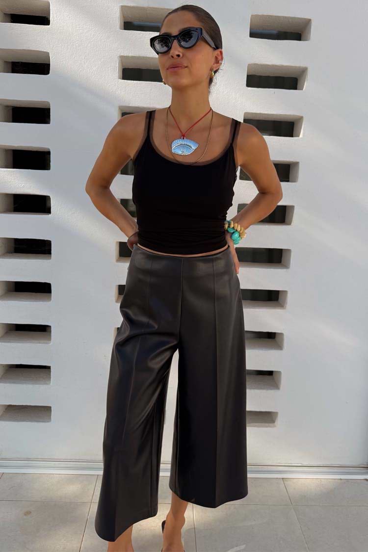 Black Vegan Leather Culottes in a wide-leg silhouette with front crease detailing, styled with a black tank top.