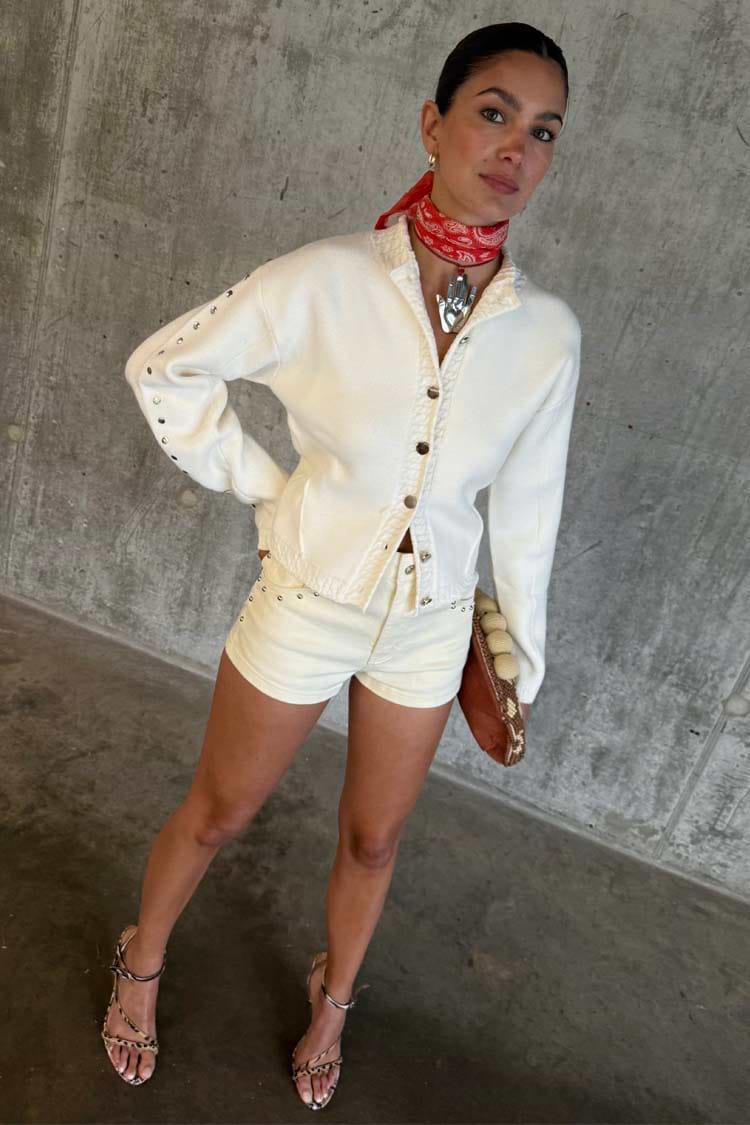Ecru Studded Hot Pant with silver studs, styled with a matching jacket and red bandana neckerchief.