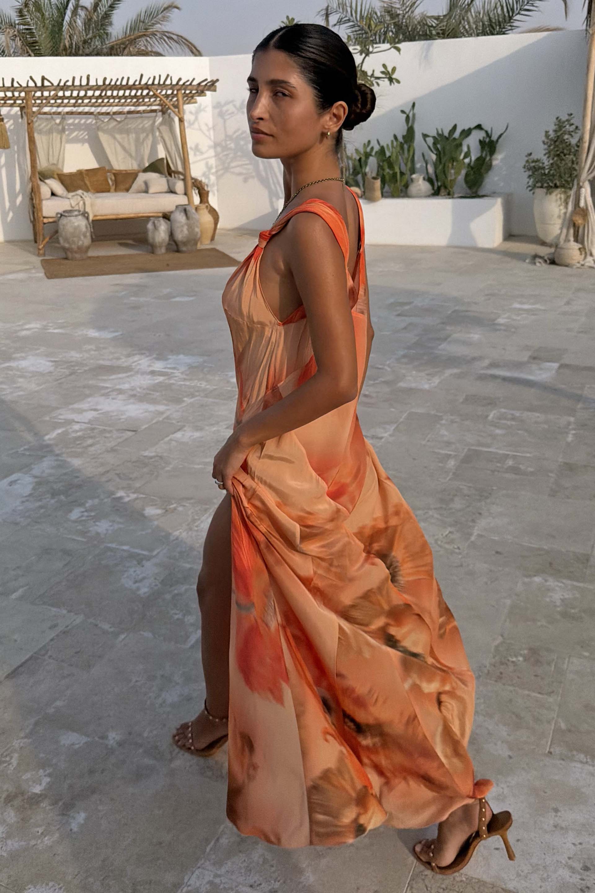 Burnt orange Blurred Floral Sofia Dress with tie-knot shoulders and a side slit, styled for a summer vacation.