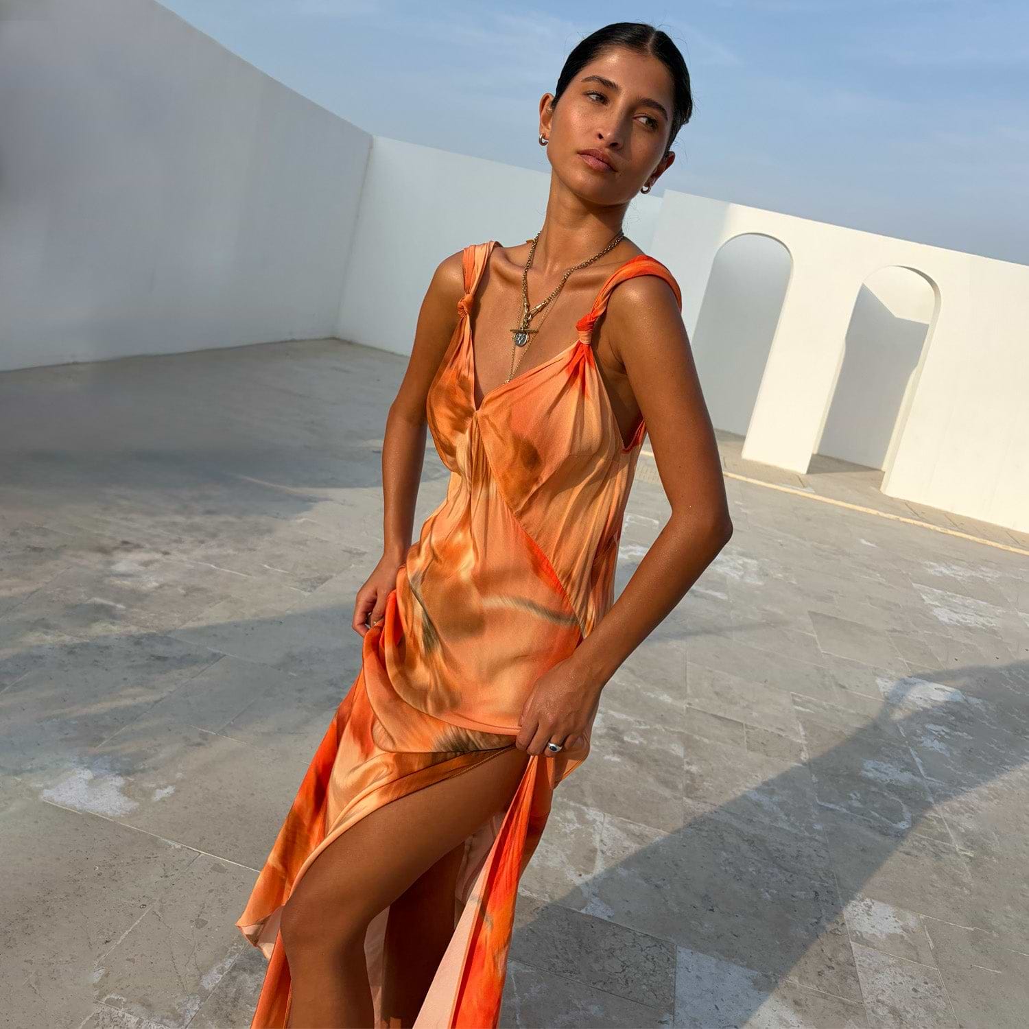 Blurred Floral Sofia Dress in burnt orange featuring tie-knot shoulders and a fluid bias-cut side slit.