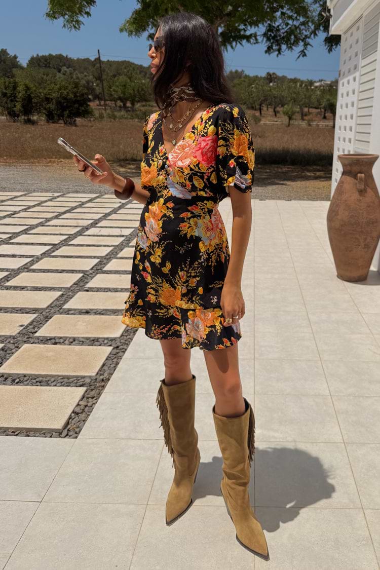 Black Sofia Mini Tea Dress with an orange and pink floral print and frill hem, styled with tan fringe boots.
