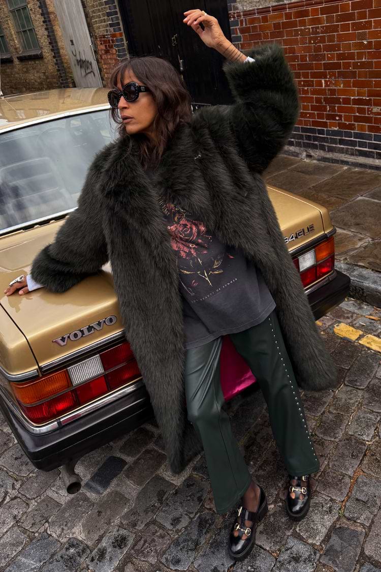 Green Faux Fur Coat in a relaxed fit, leaning against a vintage gold car on a cobblestone London street.