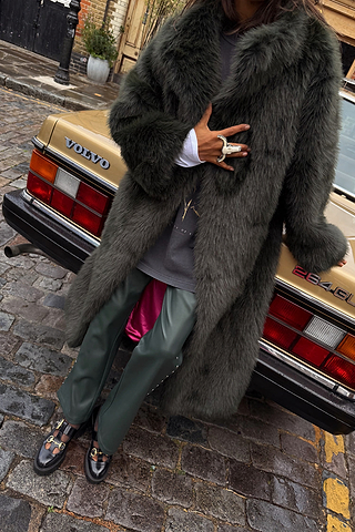 Green Faux Fur Coat with a hot pink lining, leaning against a vintage gold car for a London street style look.