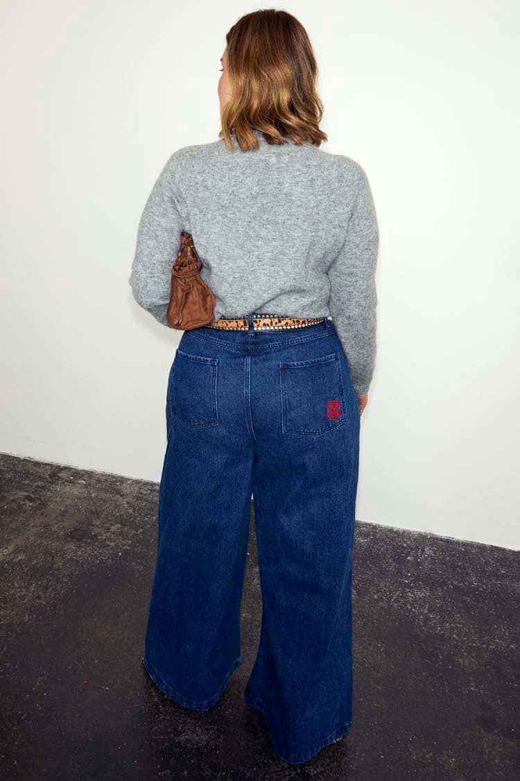 Blue Denim Pallazzo Jan Jean with a wide leg and red pocket embroidery, shown from behind for inclusive sizing.
