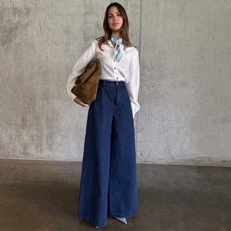 Blue Denim Pallazzo Jan Jeans in a wide-leg style, paired with a white shirt, patterned neck scarf and brown bag.