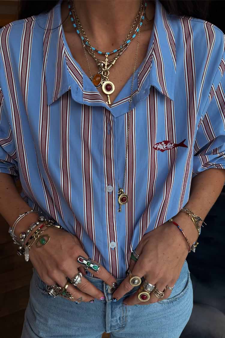 Deloris Thin Chain Key Necklace with a gold-tone key and red gem, styled with layered jewelry over a striped shirt.