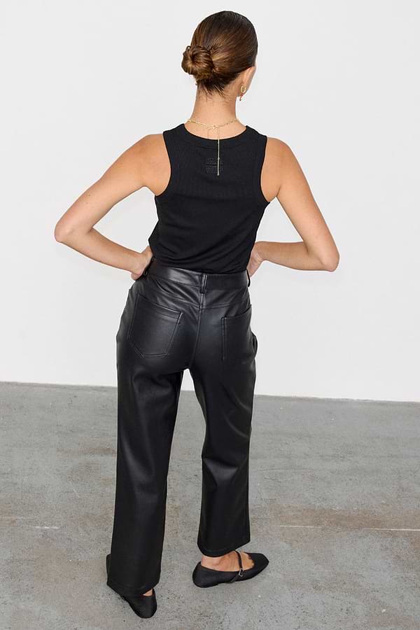 Back view of high-waisted Black Vegan Leather Trousers with a straight leg, paired with a black ribbed tank top.