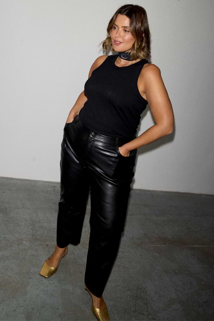 Black vegan leather trousers with a straight leg, styled with a black tank top and gold heels.