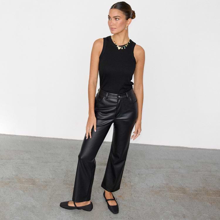 Black Vegan Leather Trousers in a straight-leg, high-waisted fit, styled with a black tank top and flats.