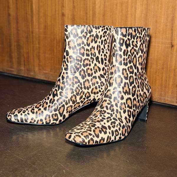 Leopard Heel Boots with a square toe and thin block heel, featuring a leopard print pattern against a wooden backdrop.