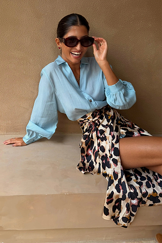 Iconic Brown Leopard Jaspre Skirt in sleek satin styled with a light blue shirt and sunglasses.