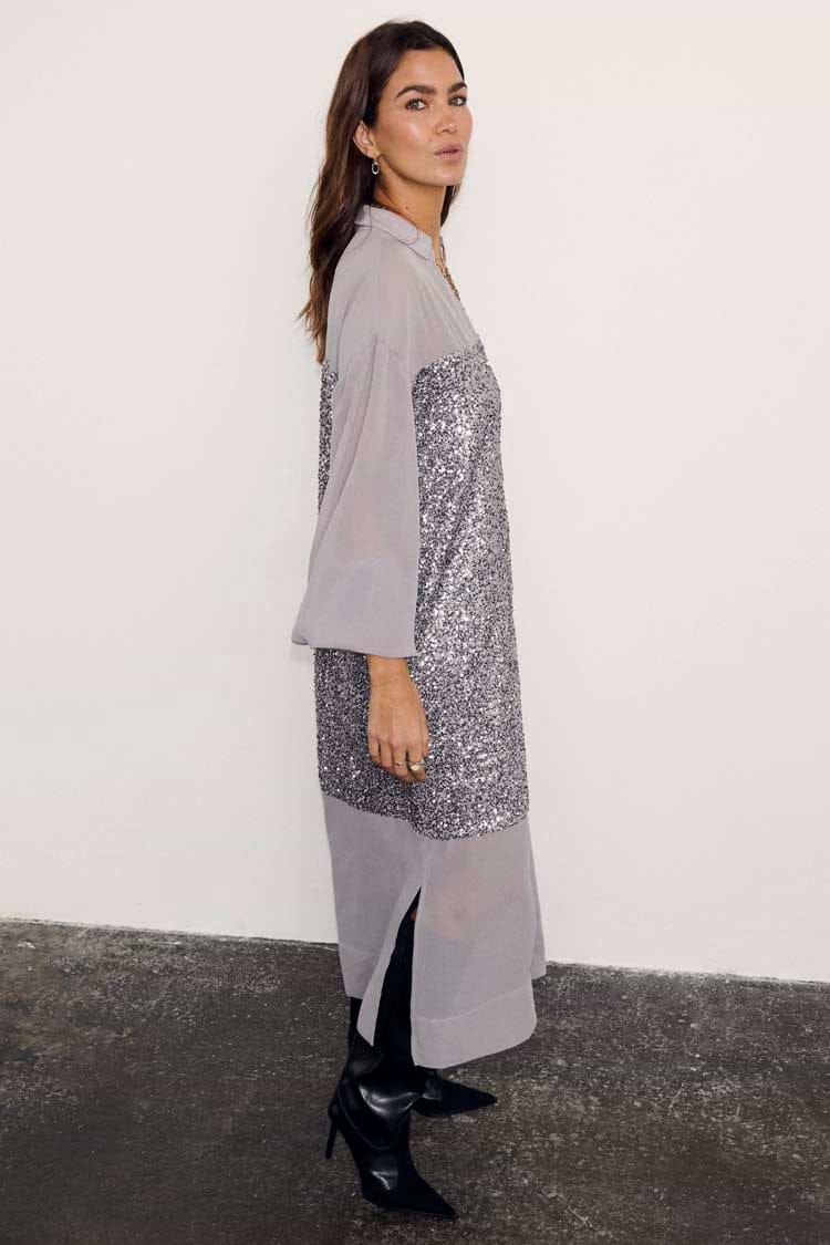 Gunmetal Sequin Lila Shirt Dress featuring silver sequins and sheer panels, styled with black pointed boots.