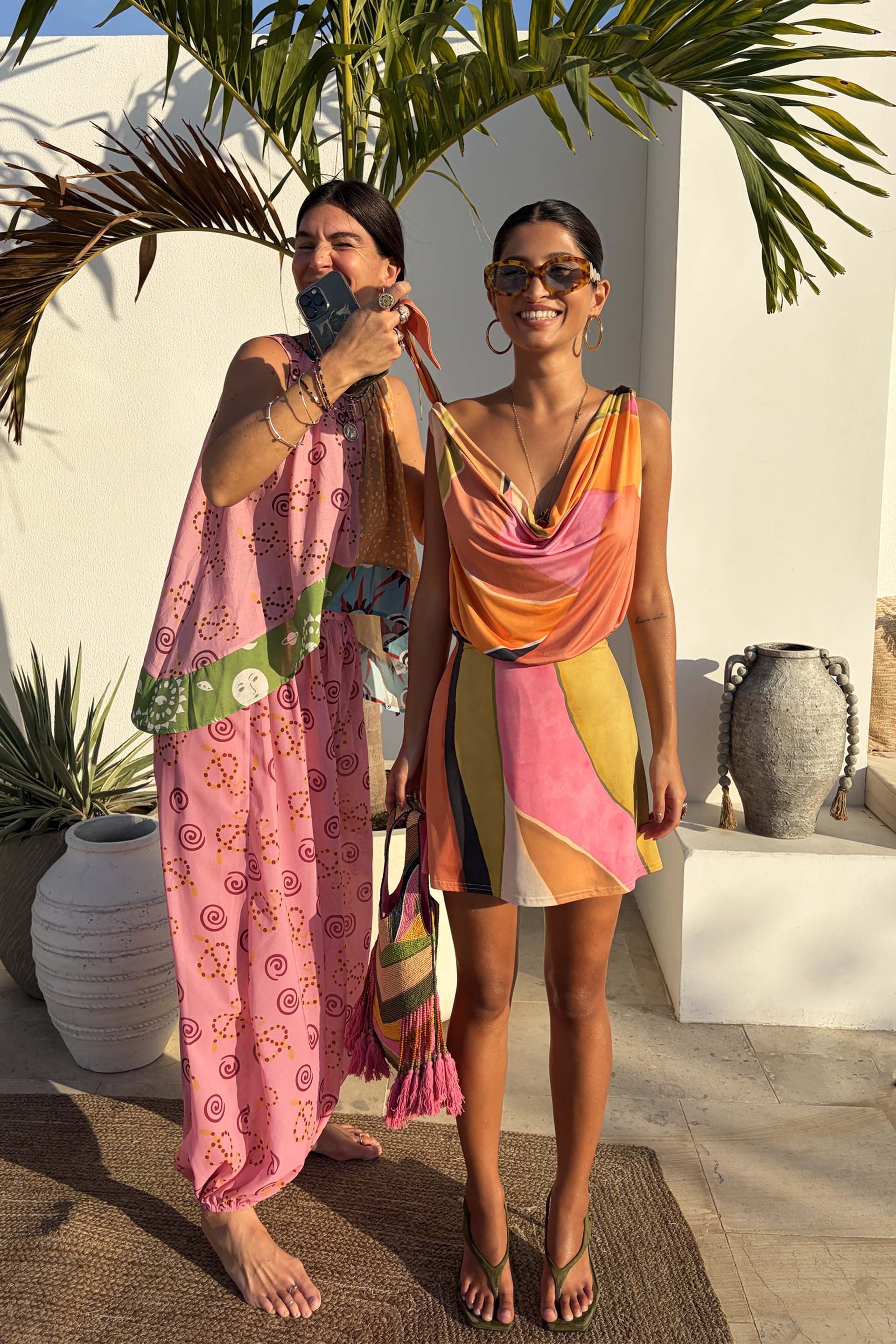 Green Abstract Leila Mini Dress with a vibrant multi-colour print and cowl neck in a sun-drenched vacation setting.