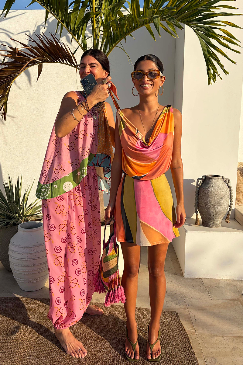 Green Abstract Leila Mini Dress with a vibrant multi-colour print and cowl neck in a sun-drenched vacation setting.