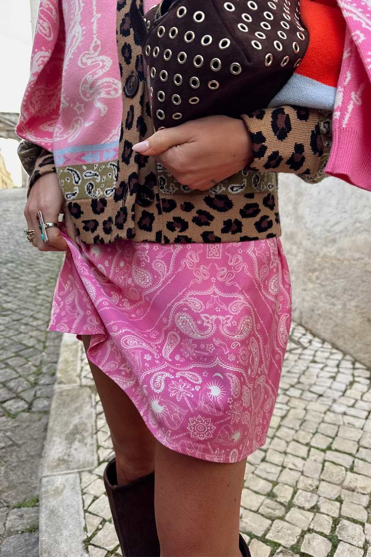 Pink Bandana Mini Dorris Skirt featuring a white paisley print, styled with a leopard print cardigan on a cobbled street.