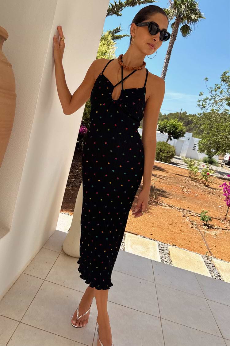 Multi Spot Megan Dress in black plisse with multicoloured flecks and cross-front straps, styled for a summer vacation.