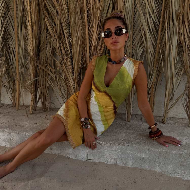 Green Ombre Deia Mini Dress in earthy green and yellow with raffia edge trim, styled for a beach holiday.