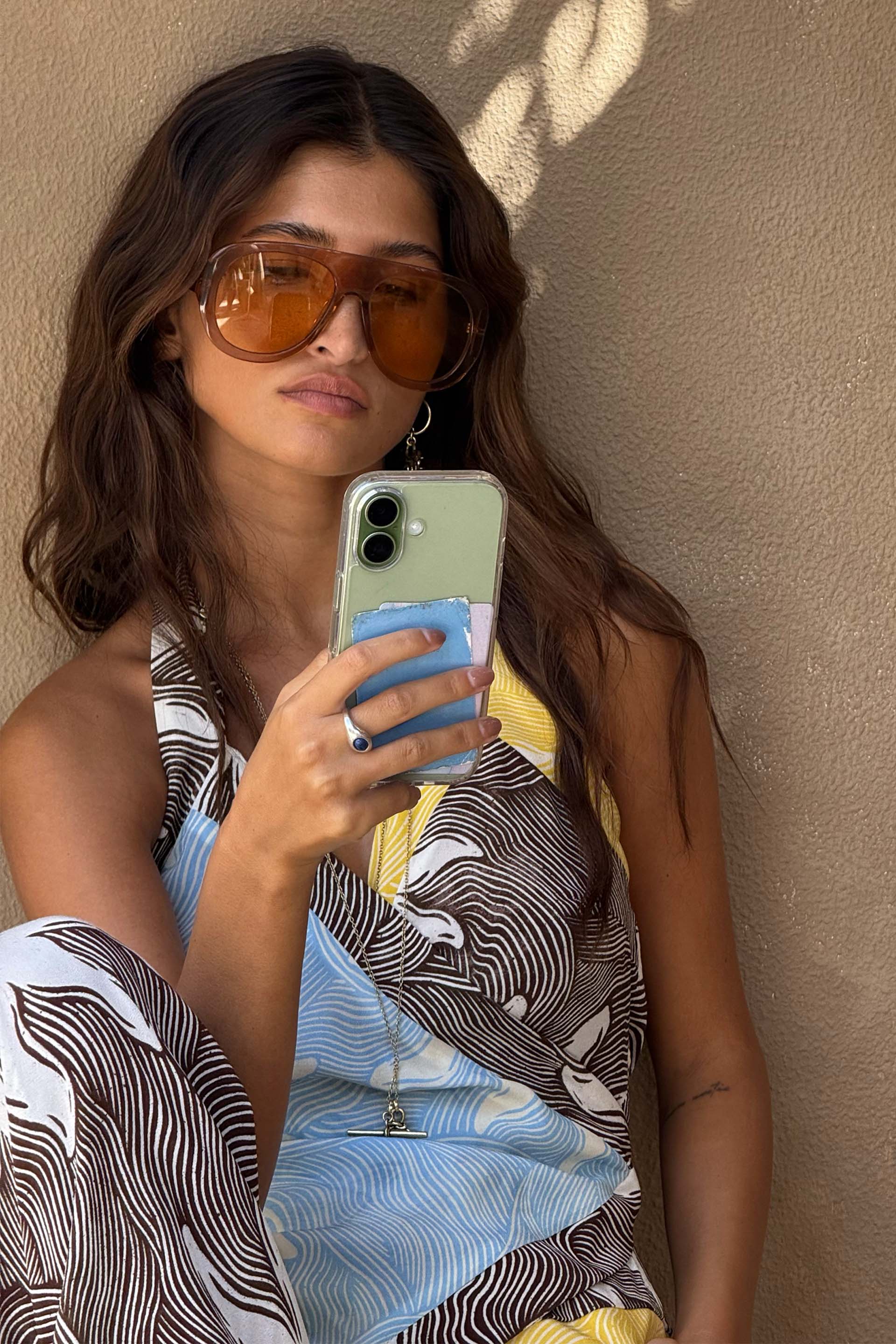 Orange Acetate Visor Sunglasses with 70s-inspired tinted lenses worn by a model in a wave print dress.