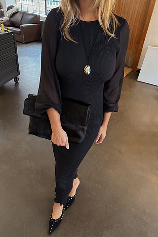 Black Plisse Perrie Dress featuring sheer sleeves and balloon cuffs, styled with a matching clutch for an evening look.