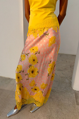 Pink Fawn Poppy Midi Maeva Skirt with yellow floral motifs and contrast lace trim, styled with silver shoes.
