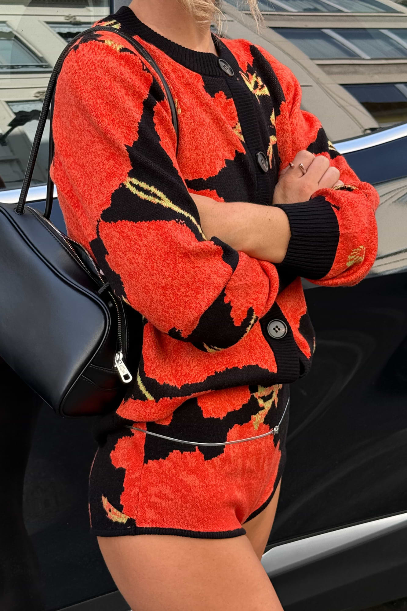 Black Poppy Cardigan with an iconic red poppy print and wide sleeves, paired with matching shorts and a black bag.