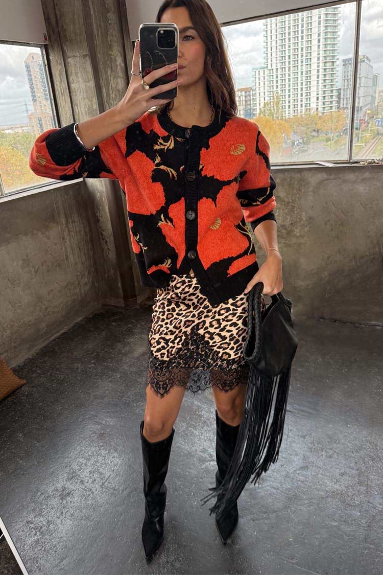 Black Poppy Cardigan with a red floral print, styled with a leopard print lace skirt and black fringed bag.