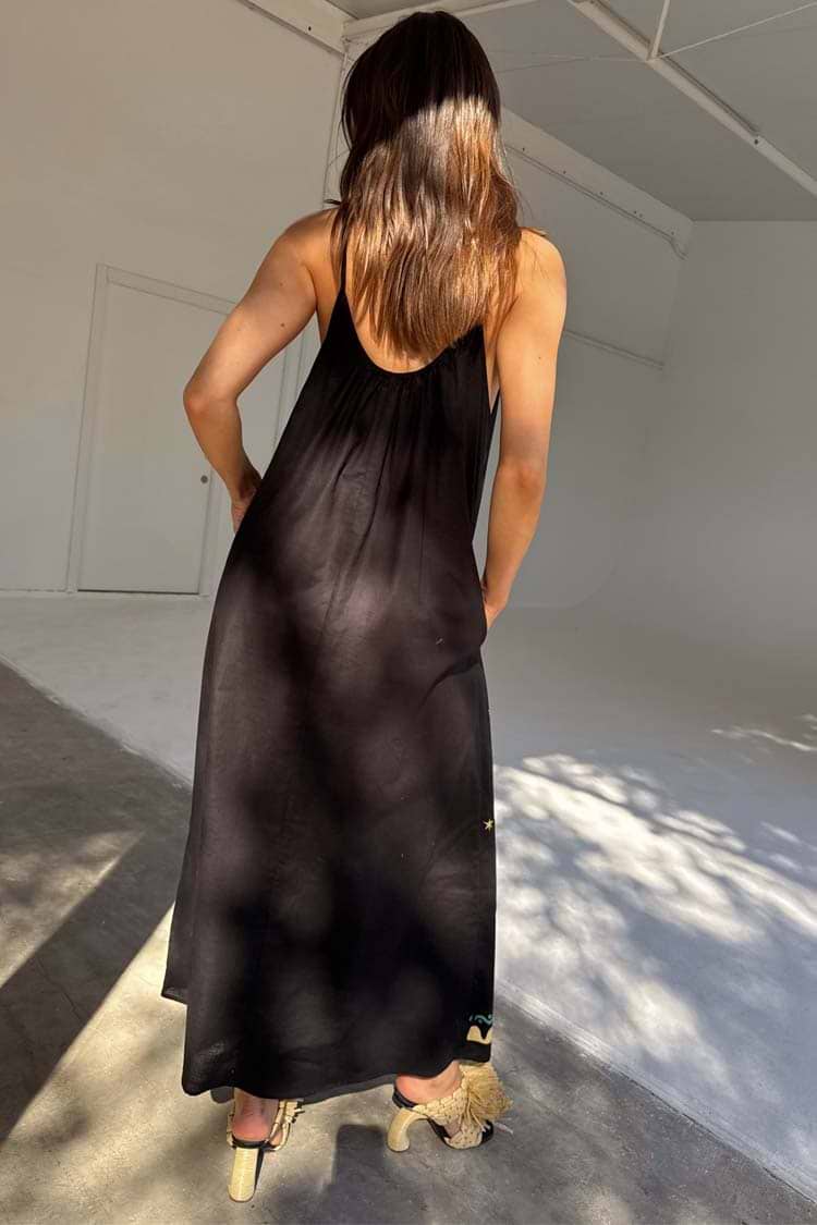 Black Rio Maxi Dress from the back, with thin adjustable straps and lightweight fabric featuring subtle tropical motifs.