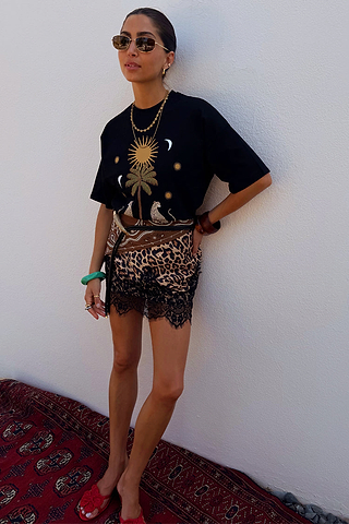 Running Wilder T-shirt in black cotton with iconic sun and leopard print, styled with a mini skirt.