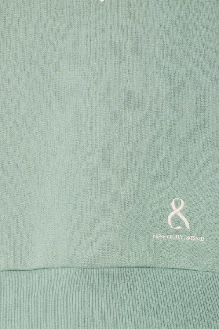 Sage green Sage Sundazed Accessible Sweatshirt detail featuring an embroidered white logo and ribbed hem.