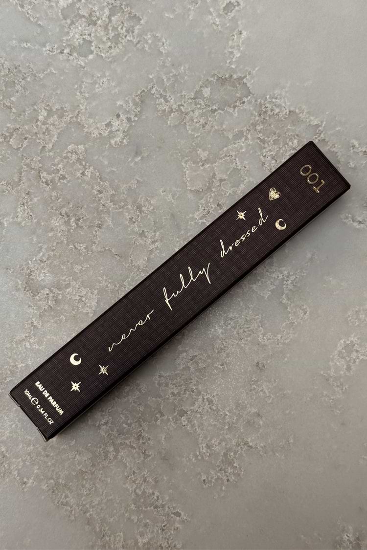 Dark brown NFD Eau De Parfum 001 10ml box with gold foil script and celestial icons on a stone surface.
