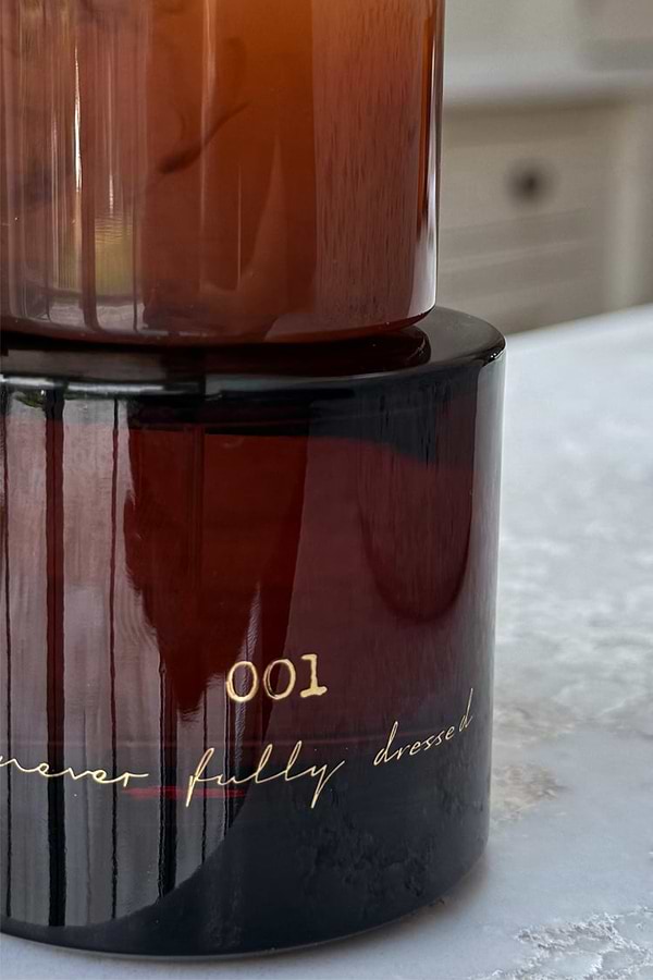 NFD Eau De Parfum 001 in an amber glass bottle featuring gold script lettering on a light stone surface.