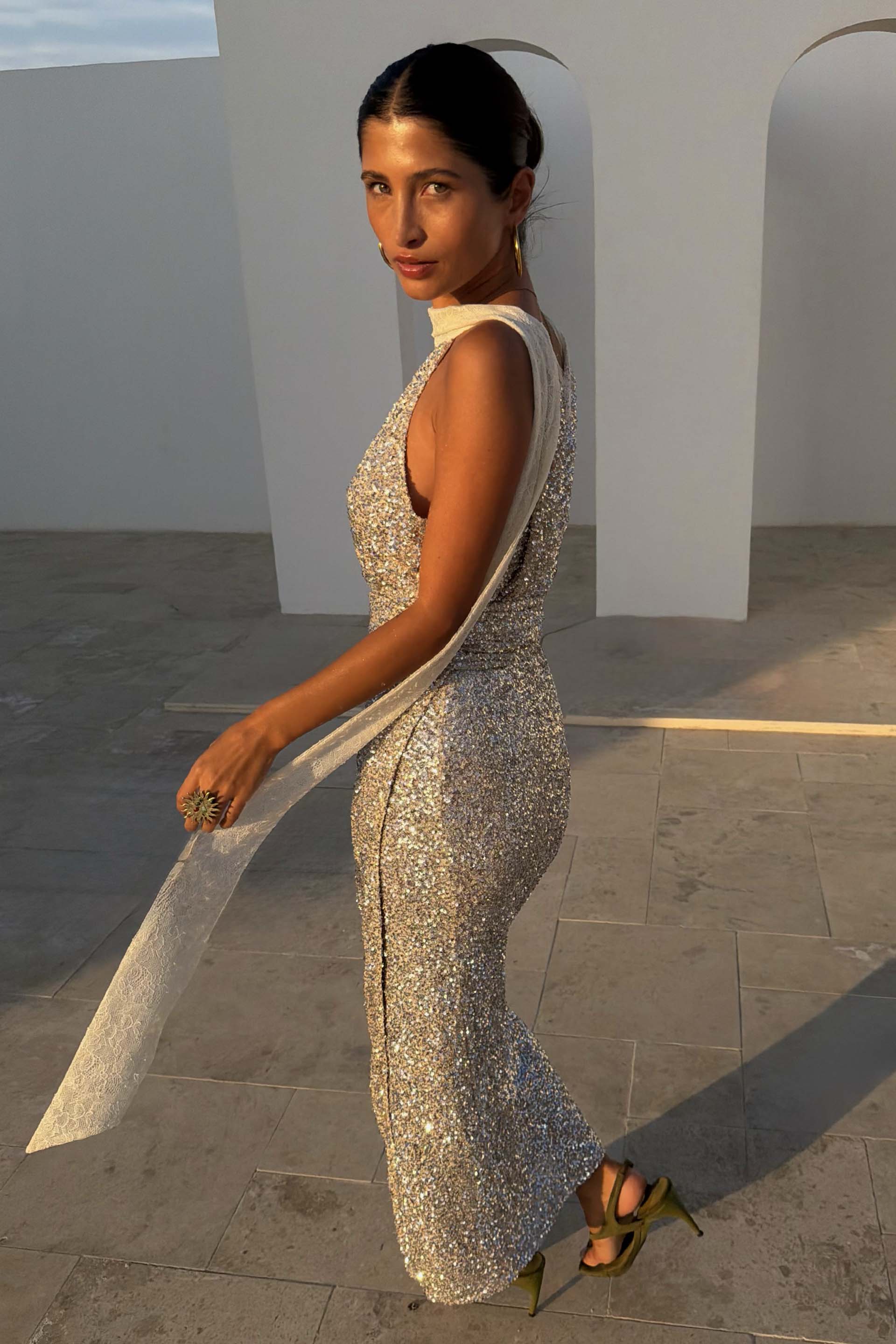 Silver Sequin Maxi Wrap Jaspre Skirt with a waist tie, styled in an outdoor architectural setting.