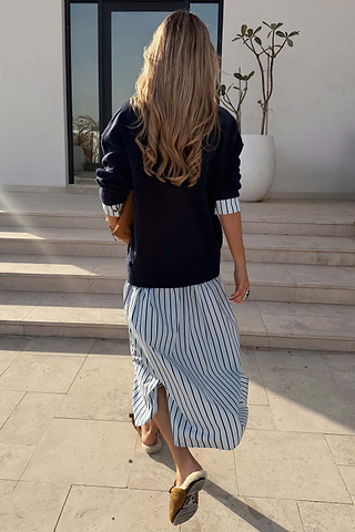 Navy soft-touch knit jumper dress with a blue striped cotton skirt, shown from behind walking up steps.