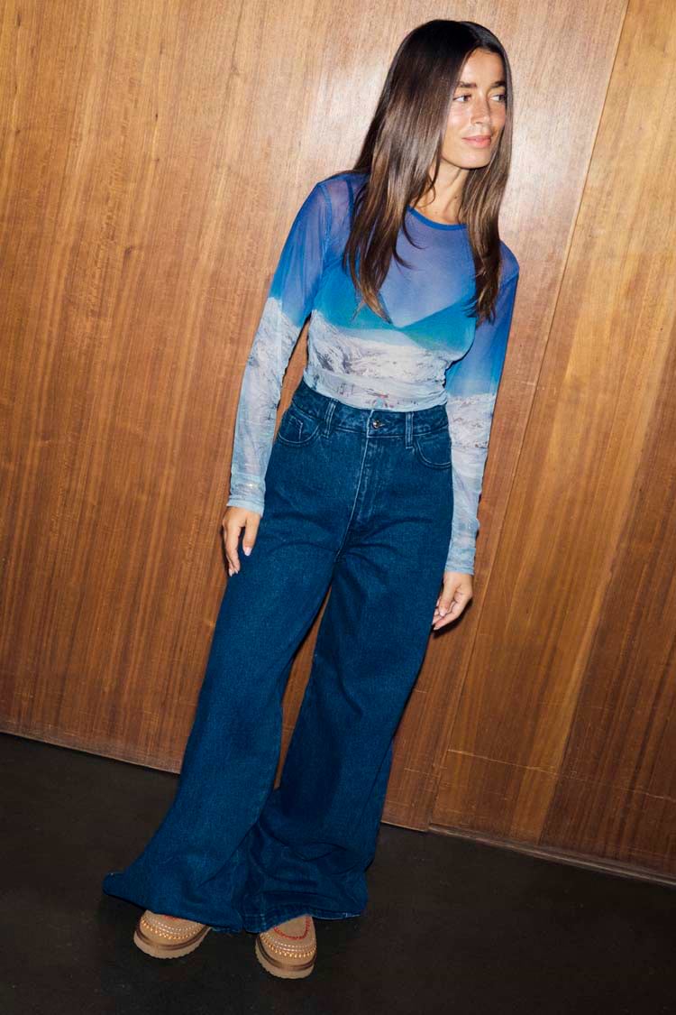 Blue Ski Slopes Mesh Long Sleeve Top with a sheer mountain print, paired with dark wash wide-leg denim jeans.