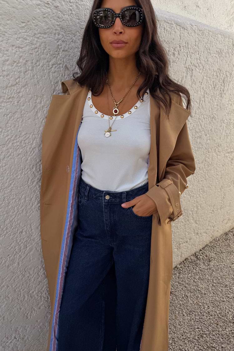 White Studded Rib Vest with gold stud detailing, styled with a camel trench coat and dark denim jeans.