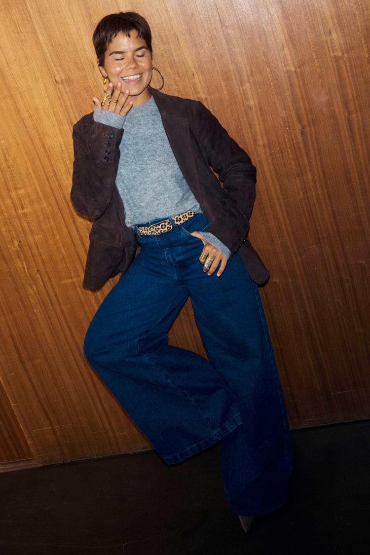 Chocolate Suede Jacket in rich brown, styled with wide-leg denim and a leopard print belt against wood panelling.