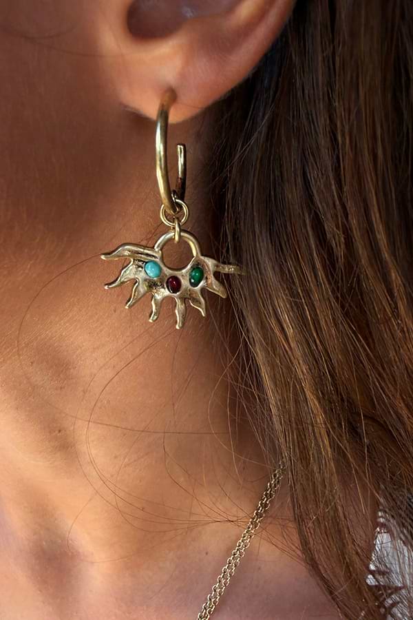 Gold-tone Deloris Sun Hoop Earrings featuring iconic sun motifs and semi-precious stones, worn on the ear.