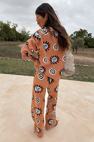 Tan Sun Trousers and matching knit jumper featuring Mediterranean-inspired sun motifs, viewed from behind.