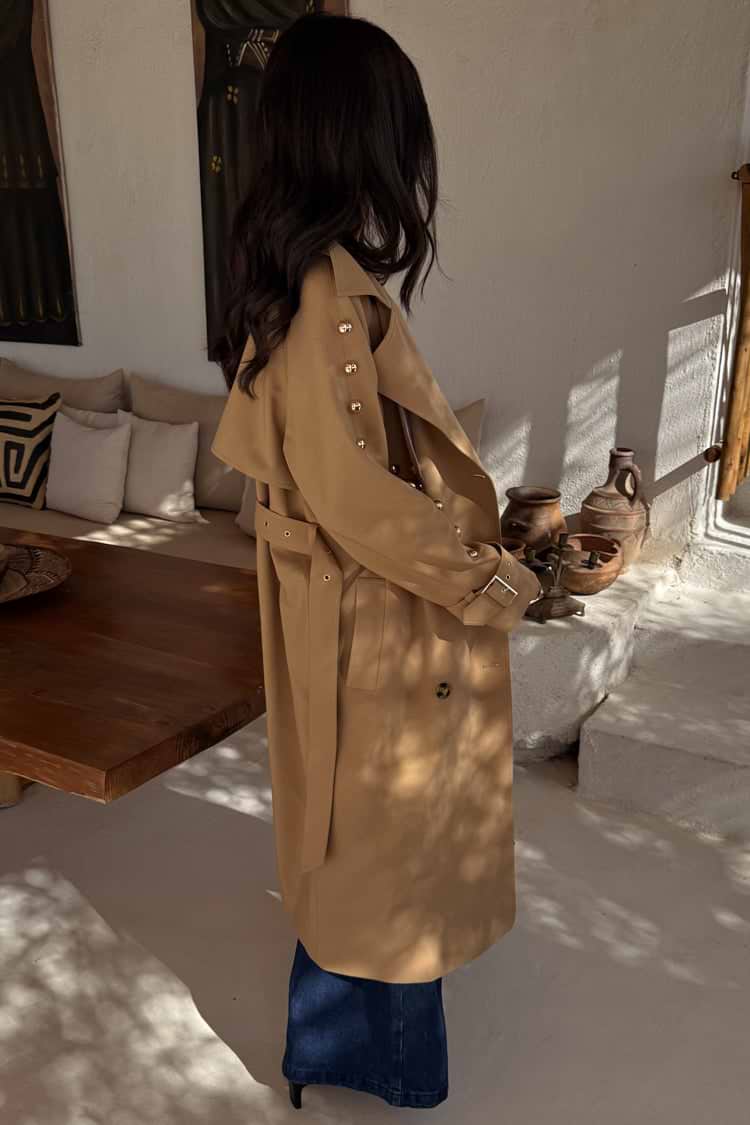 Tan Trench Coat with gold studs on the sleeve and a waist belt, worn by a model who is 5ft7” and wears size M.
