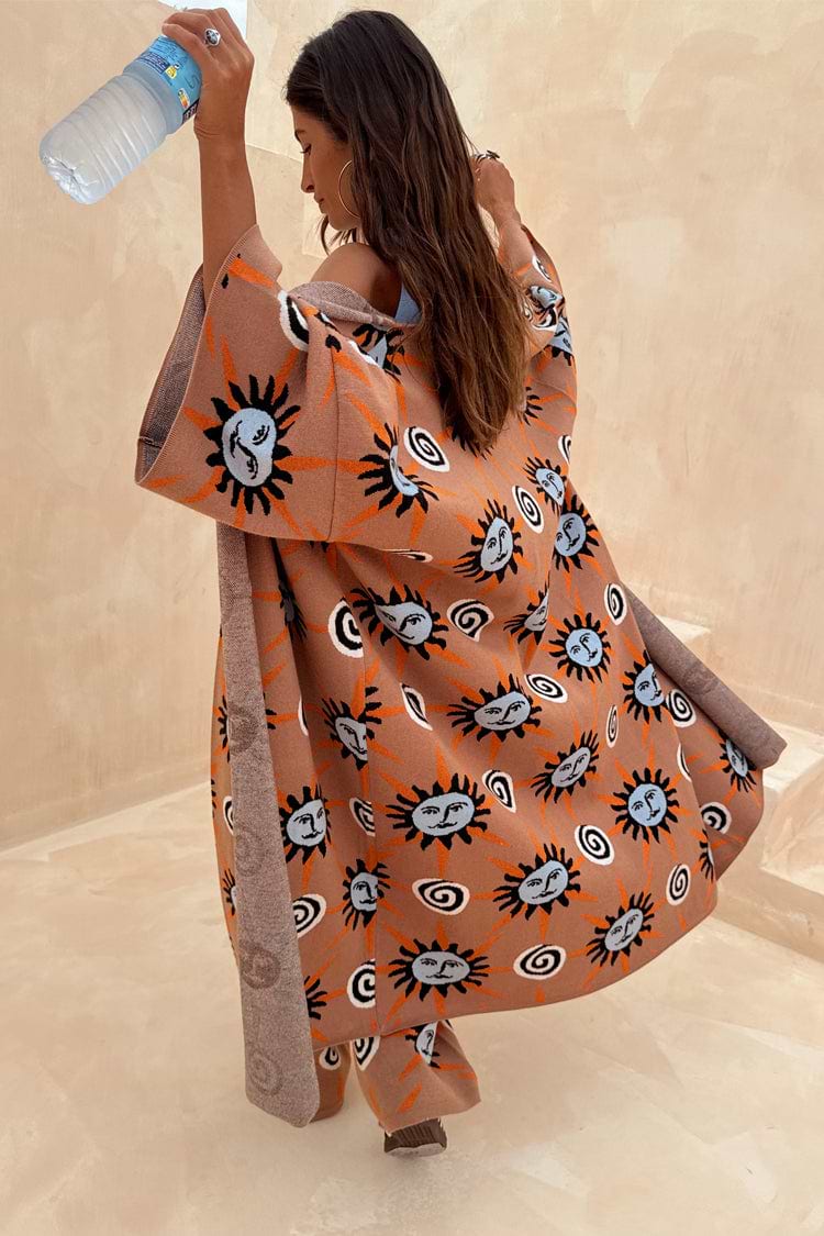 Oversized Tan Sun Cardigan featuring hand-painted Mediterranean sun motifs and wide sleeves in an outdoor setting.