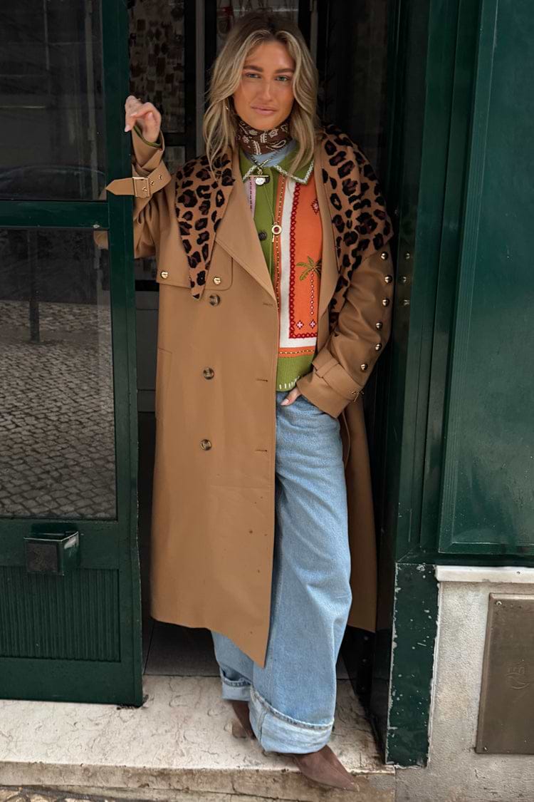 Tan Trench Coat with gold studs and leopard scarf, a statement staple styled over a green knit and wide-leg jeans.