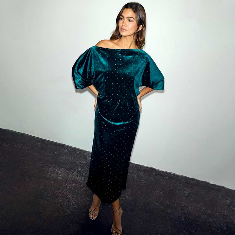 Emerald Velvet Tilly Dress with an off-shoulder neckline, voluminous top and sparkling detail on a model.